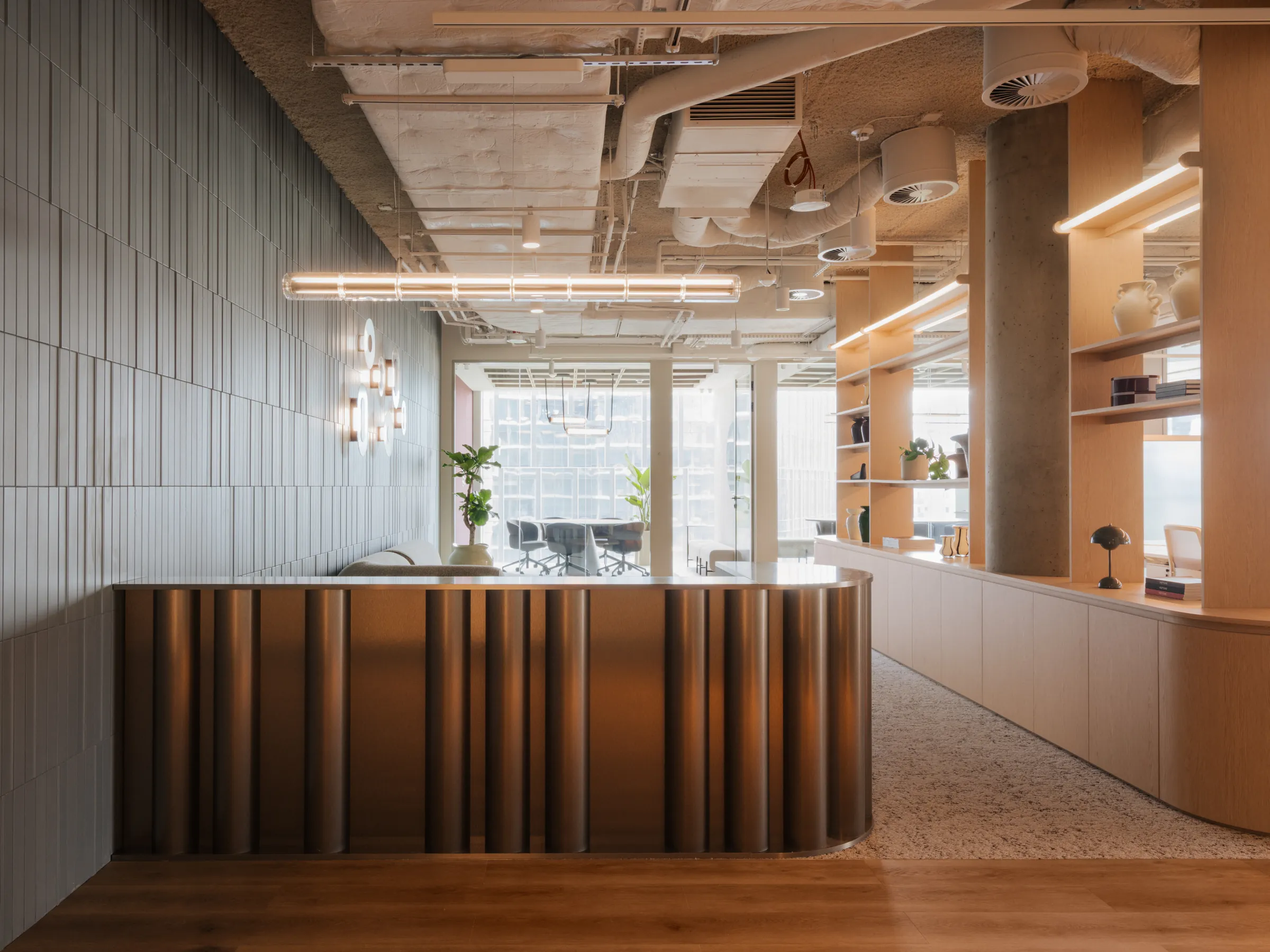 Fifth-floor reception: desk, shelving and a sage wall with lamps